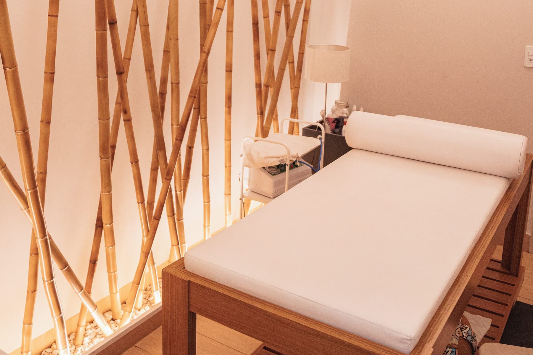Treatment bed with a bolster pillow against a softly lit bamboo wall
